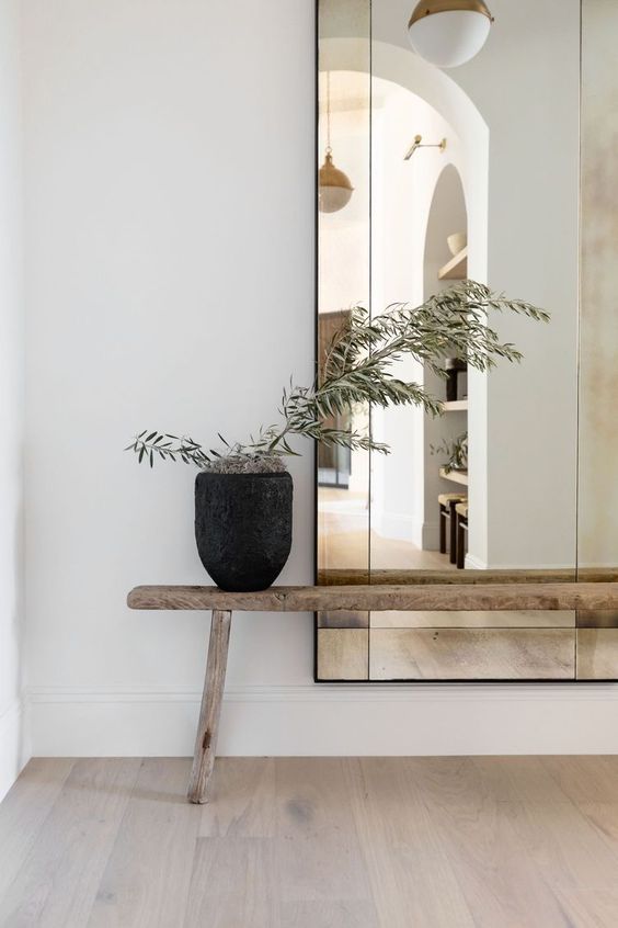 Un grand miroir et un banc en bois pour sublimer le mur blanc